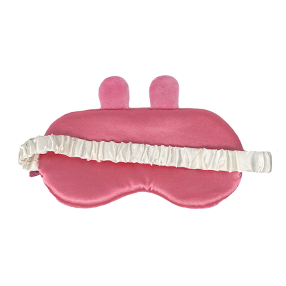 A pink satin sleep mask with two small upright bunny ears on top and a white ruffled elastic strap, shown on a plain white background.